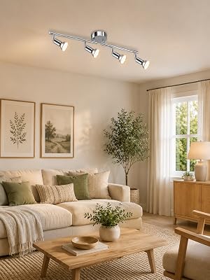 Modernes Wohnzimmer mit beigem Sofa, Holzmöbeln, gerahmten botanischen Kunstwerken, Topfpflanzen und einer Deckenleuchte mit vier Lichtern und verstellbaren Strahlern, die an einer neutralen Decke montiert sind.