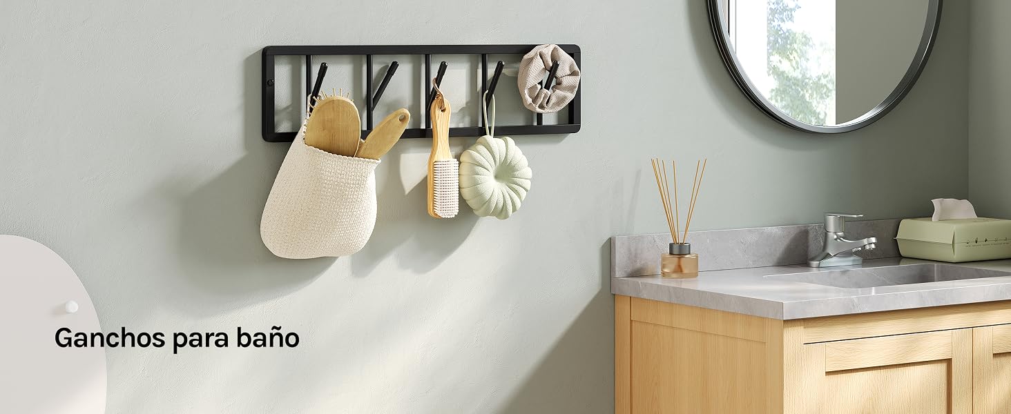 El texto dice «Ganchos para baño». Barra metálica negra montada en la pared con cuatro ganchos para guardar toallas y accesorios de baño de color beige en un baño moderno con tocador de madera.