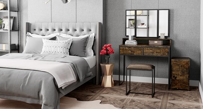 Modern bedroom interior with gray upholstered bed, wooden vanity, wall-mounted lights, and industrial-style shelving units.