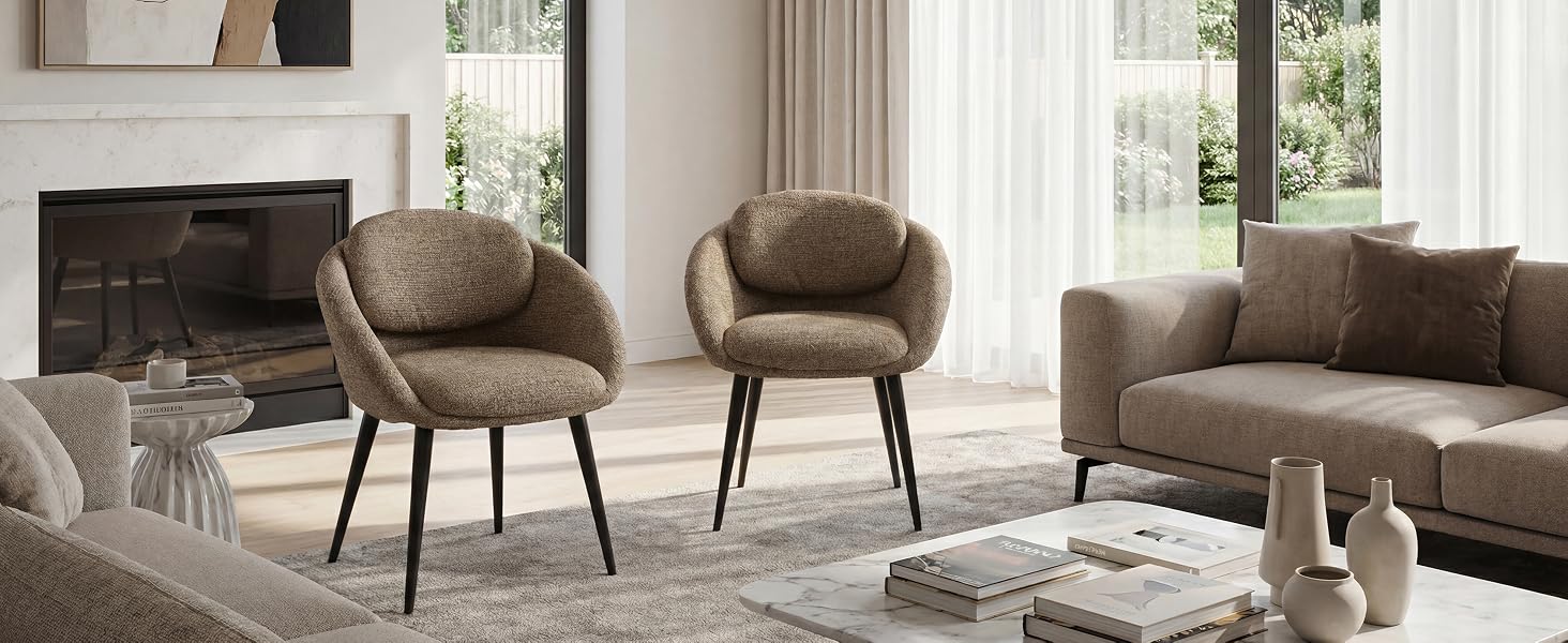 L'intérieur du salon moderne comprend des fauteuils rembourrés bruns, un canapé sectionnel gris, une table d'appoint en bois, des objets de décoration et de grandes fenêtres avec lumière naturelle et rideaux.