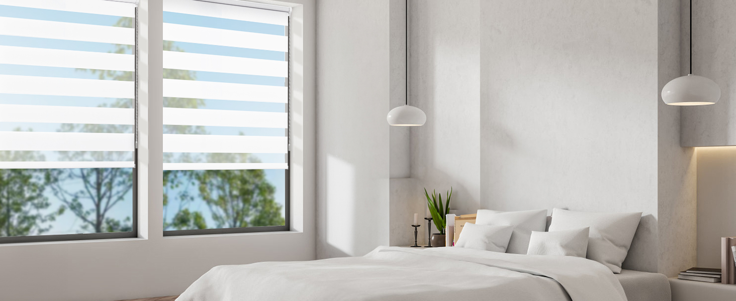 Intérieur de chambre moderne avec murs blancs, grandes fenêtres horizontales avec stores à rayures, literie grise et suspensions.