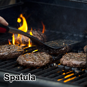 Spatule en métal retournant les galettes à hamburger sur une grille enflammée, avec des marques de gril visibles et
