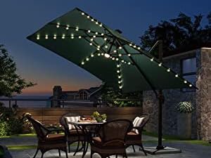 Large outdoor patio umbrella with built-in LED lights illuminating a dining area at dusk, featuring dark green canopy.
