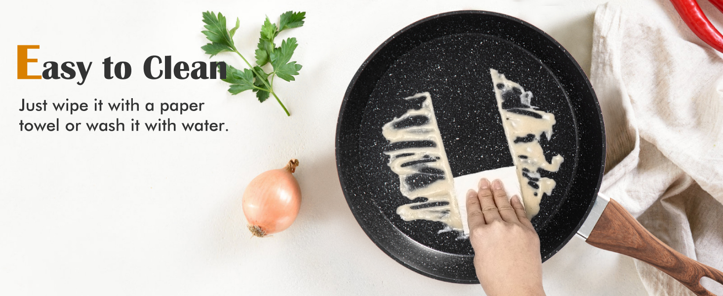 Die antihaftbeschichtete Bratpfanne wird mit einem Papiertuch gereinigt und zeichnet sich durch eine einfache Reinigungsfunktion aus. Petersilie und Zwiebel sind in der Nähe sichtbar