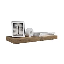 Wooden floating shelf displaying a framed black and white lighthouse photograph, a white decorative object, and a book.