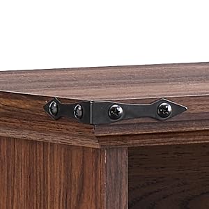 Plans rapprochés de la quincaillerie d'un meuble en bois foncé, montrant des supports de montage ou des charnières en métal noir contre une surface en bois.