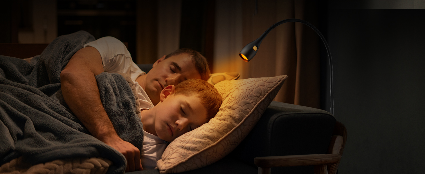 Person resting in bed, illuminated by warm bedside lighting in a dark room.