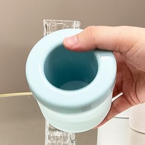 une main tenant une tasse avec un bord bleu.