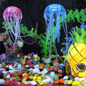Aquarium decoration set featuring glowing pink and blue jellyfish ornaments, artificial plants, yellow pineapple house, and colorful gravel substrate.