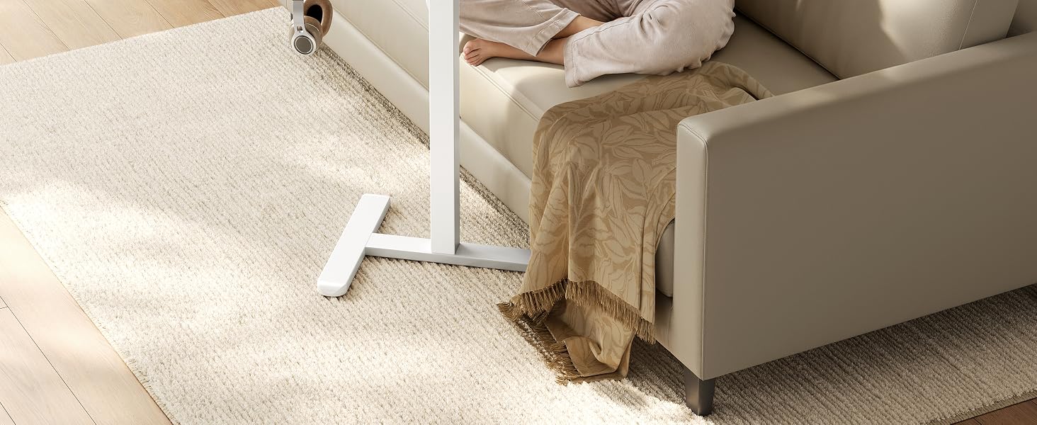 Primer plano de la pata o soporte de un mueble blanco colocado junto a la base del sofá tapizada de color beige, que muestra detalles de la construcción del mueble y el punto de conexión contra el suelo alfombrado.