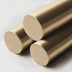 Three cylindrical gold-colored metal rods displayed diagonally, showing brushed metallic finish and circular end surfaces against light background.