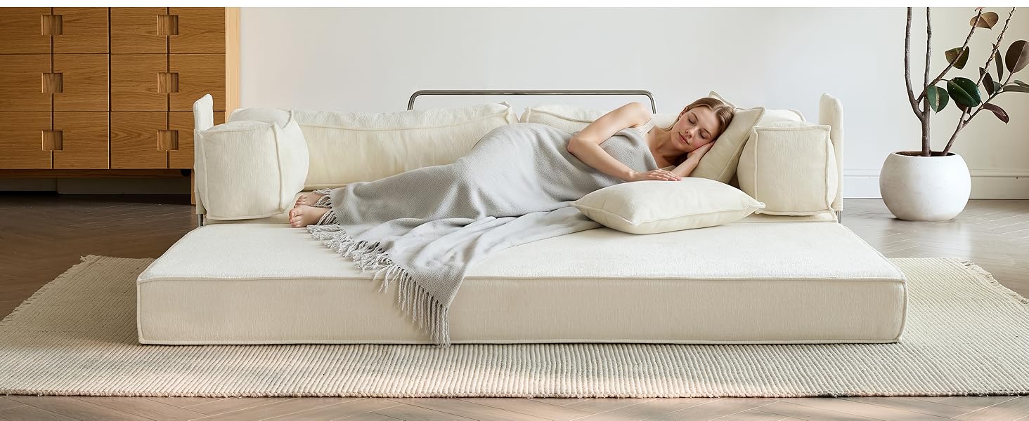 Mujer en pijama azul claro recostada en una cama con plataforma de color crema con ropa de cama y almohadas blancas, decoración de dormitorio elegante con paneles de pared de madera y accesorios de cerámica blanca a la vista.