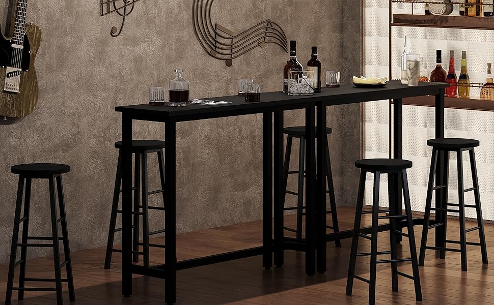 Allestimento da bar in stile industriale con tavolo alto in legno, sgabelli in metallo nero e lampade a sospensione. Bottiglie e bicchieri visibili sugli scaffali