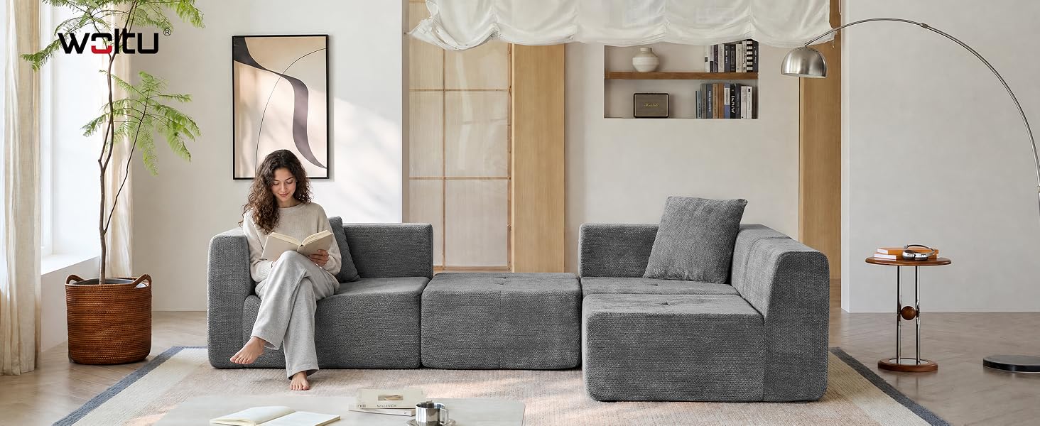 Der Text lautet: „AURELI“. Modernes Wohnzimmerinterieur mit Frau, die auf einem grauen L-förmigen Ecksofa sitzt, mit hölzernem Beistelltisch, Topfpflanze, runder Stehlampe und neutraler Wandverkleidung in einer modernen Wohnumgebung.
