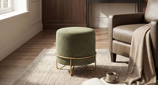 Cadre de salon moderne comprenant un fauteuil rembourré vert olive au design incurvé, posé sur un tapis beige avec une couverture.