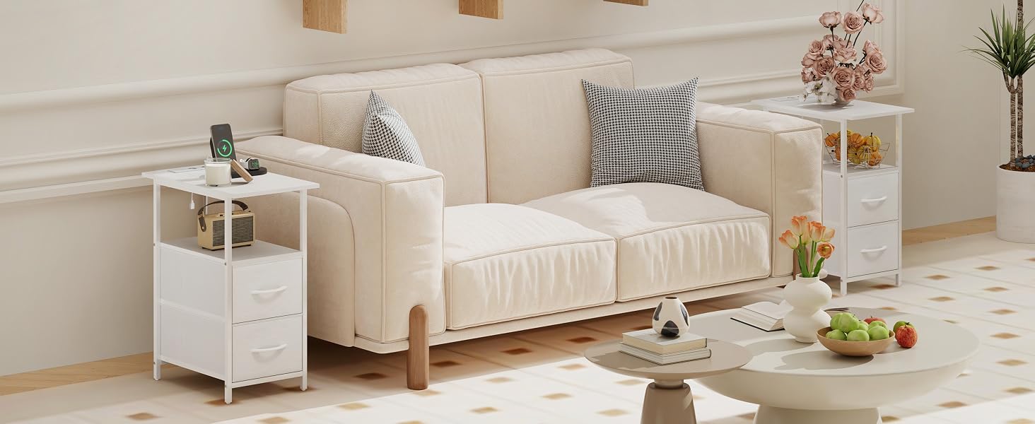 Canapé rembourré moderne de couleur crème avec pieds en bois et table d'appoint blanche dans un salon minimaliste avec coussins décoratifs et accessoires.