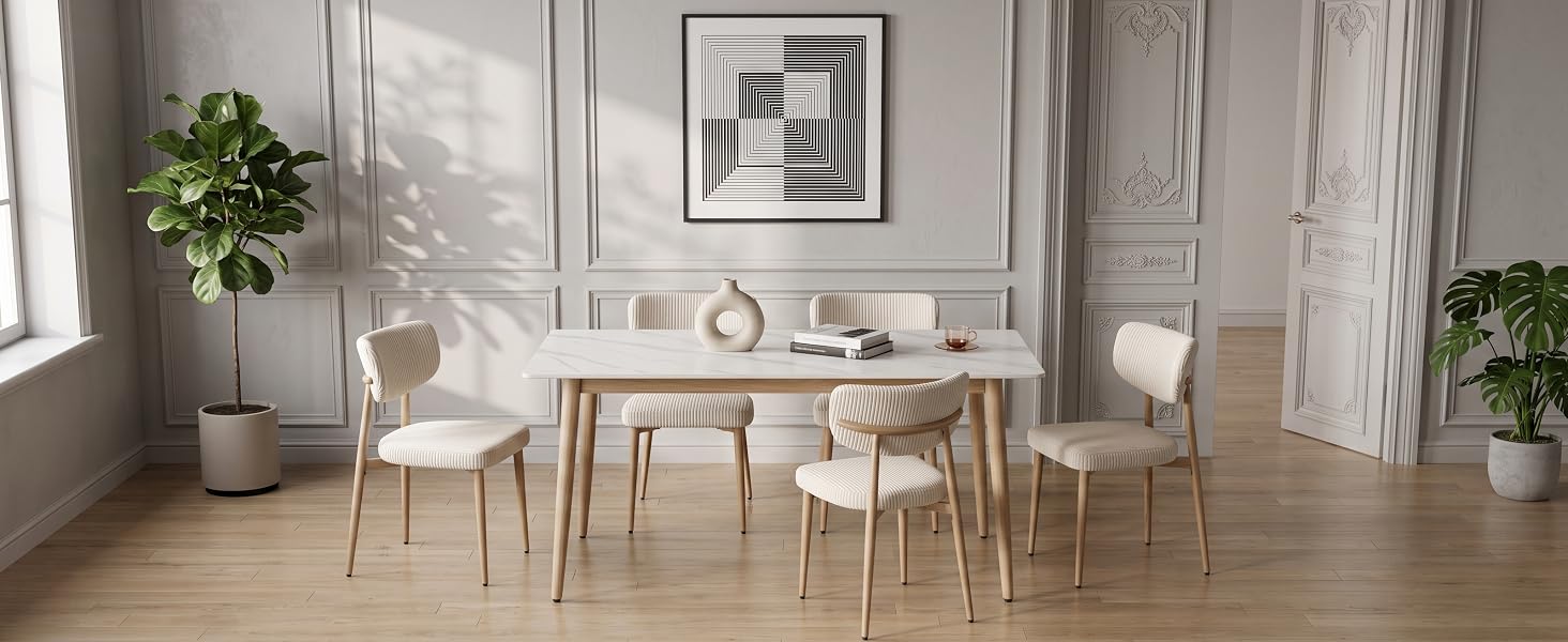 Modernes minimalistisches Esszimmerinterieur mit weißen Wänden, rundem weißen Esstisch, hellen Holzstühlen, Topfpflanzen und hellem Tageslicht aus den Fenstern.