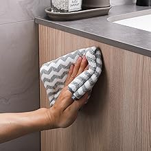 une personne nettoyant une armoire de toilette avec un chiffon.