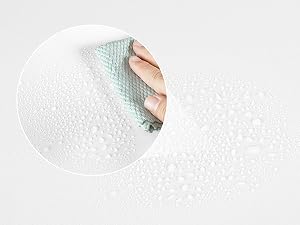 Vista de cerca de una toalla de papel o un paño de limpieza que limpia una superficie blanca texturizada con gotas de agua visibles.
