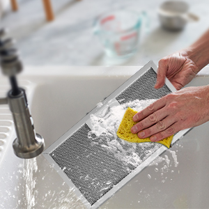 Laver la vaisselle à la main dans un évier avec une éponge jaune, en suivant une technique de nettoyage appropriée à l'eau et au savon.