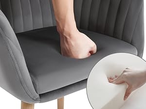 Grey upholstered chair with demonstration of cushion firmness test, showing hand pressing into seat material with inset detail view.