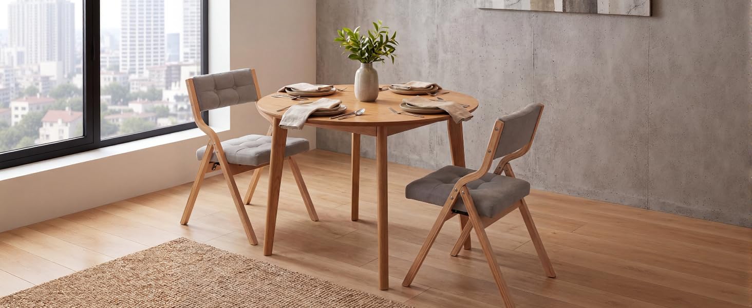 Modern dining setup with round wooden table and matching chairs in minimalist room with large windows and concrete wall feature.