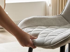 Gros plan des mains touchant un couvre-matelas ou un surmatelas blanc matelassé, ce qui montre la texture et la structure de sa surface douces et rembourrées.
