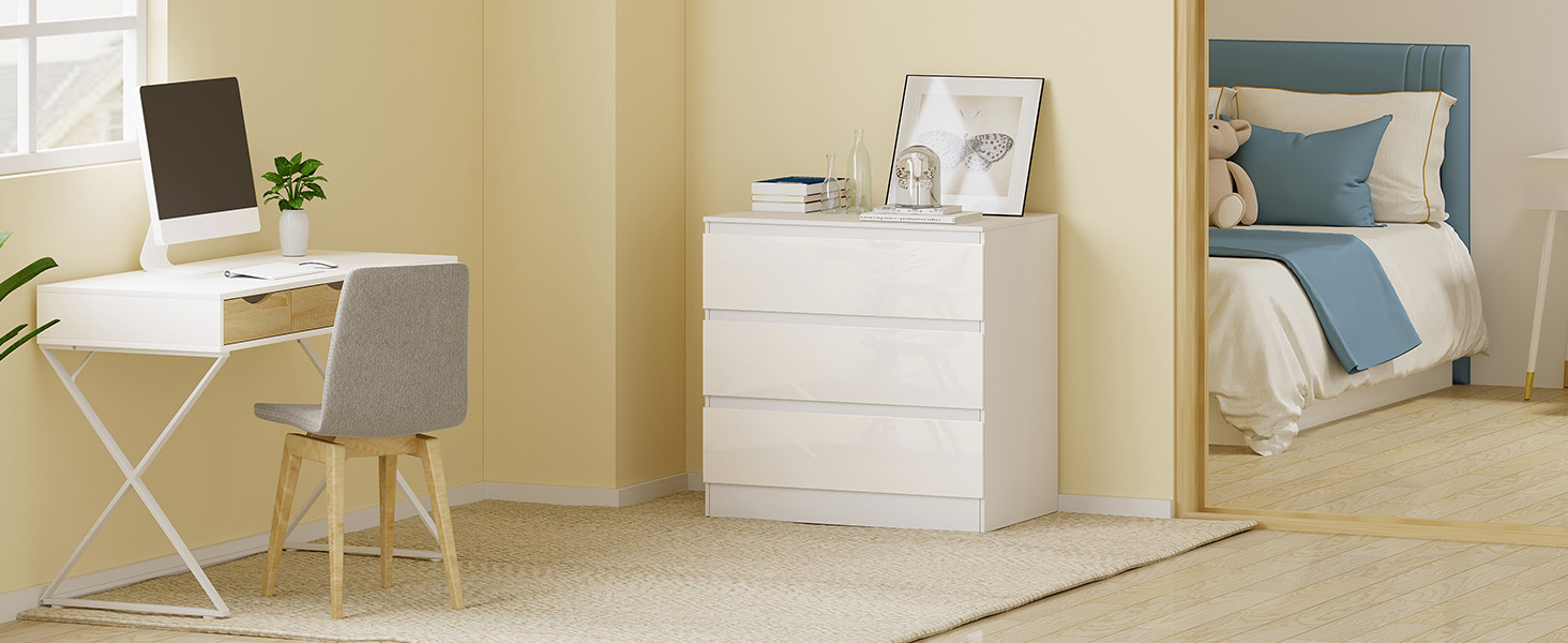 Modern home office space with white furniture including a desk, chair, dresser, and bed with blue accent bedding against beige walls.