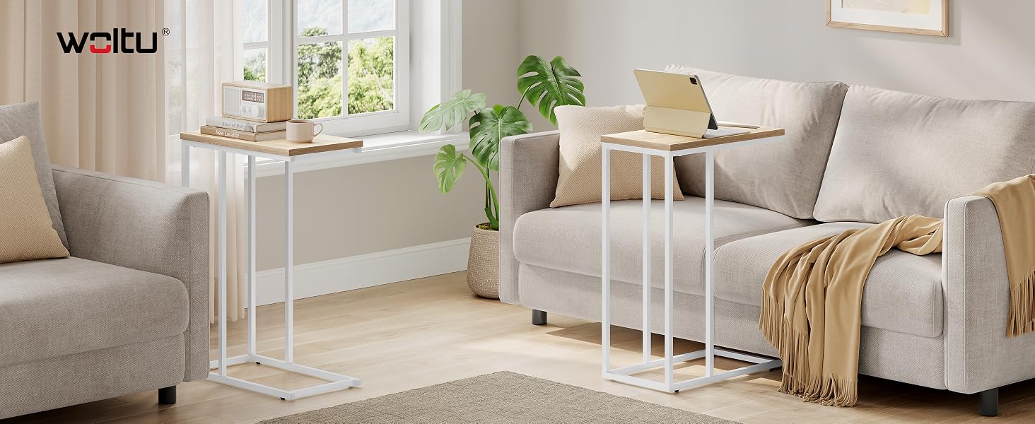 Two white metal side tables with wood-grain tops in a living room setting. Tables have C-shaped bases that slide under sofas for convenient placement.