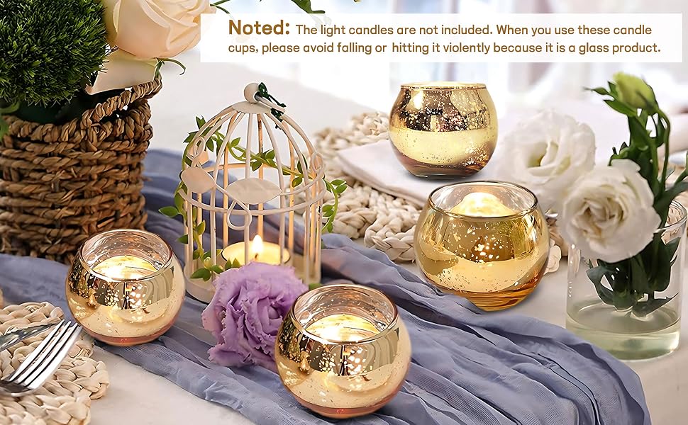 Portacandele decorativi, tra cui candele votive in vetro color oro e una lanterna bianca a forma di gabbia per uccelli su un tavolo decorato con fiori. Nota: avvertenze sulla fragilità dei prodotti in vetro.