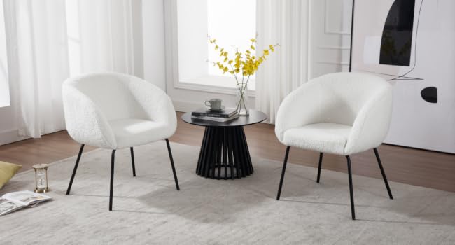 Two white, plush accent chairs with curved backs and black metal legs, positioned around a small black side table in a bright living room setting.