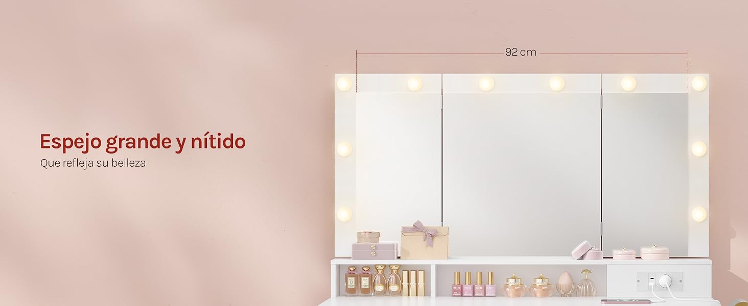 El texto dice «Espejo grande y nítido» y «92 cm x 70 cm». Espejo grande iluminado con luces LED integradas montado en una pared rosa sobre el tocador del baño con estanterías.