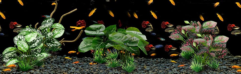 Aquarium decor featuring artificial green plants and scattered orange elements against black gravel background, creating an underwater scene effect.