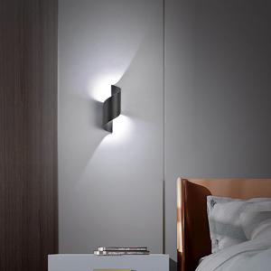 éclairant un coin de chambre. Le design blanc rectangulaire projette des faisceaux lumineux vers le haut et vers le bas contre un mur gris.