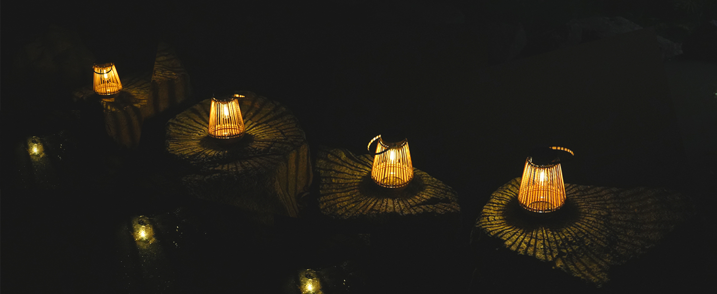 Rangée de lanternes tissées illuminées sur une surface sombre, créant une lueur chaleureuse. Les lanternes ont des motifs complexes et projettent des motifs lumineux circulaires autour de leur base.