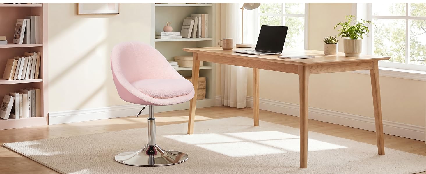 Moderna configuración de oficina en casa con silla decorativa acolchada de color rosa con patas de madera, escritorio de madera natural con computadora portátil, estantería y ventana luminosa con iluminación natural en un interior minimalista.