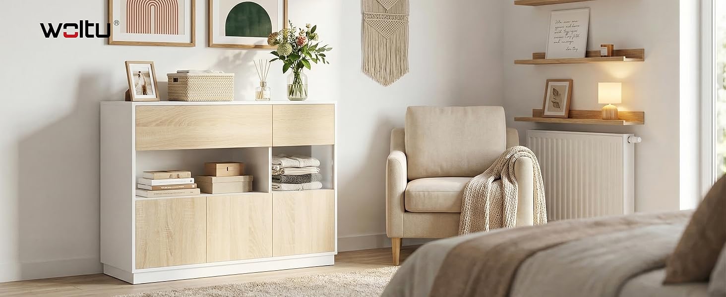 Der Text lautet „Bild 6“. Helles, minimalistisches Wohnzimmerinterieur mit weißen Möbeln, gewebten Wandbehängen und Holzregalen mit Dekorationsgegenständen.