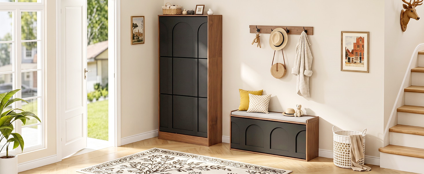 Intérieur d'entrée moderne avec armoire en bois foncé avec panier de rangement tressé, crochets muraux avec objets suspendus, œuvres d'art encadrées, plantes en pot et lumière naturelle visible par la fenêtre.