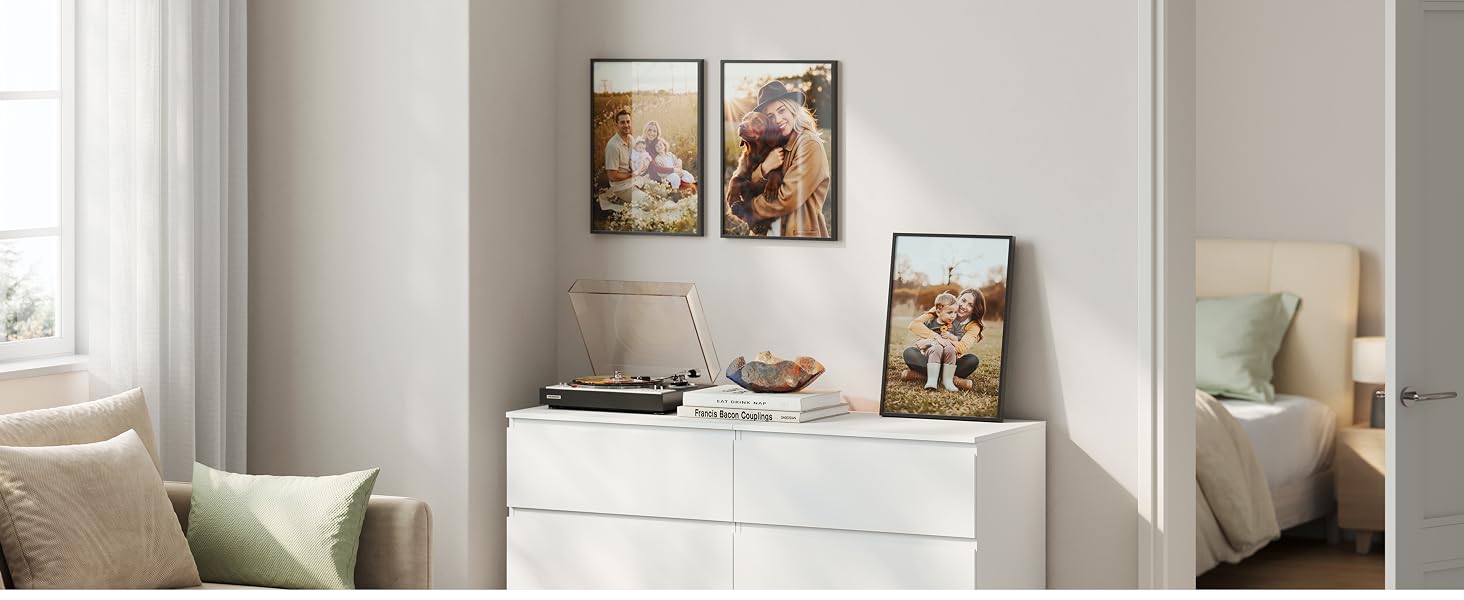 Spazio interno moderno con contenitore bianco contro una parete grigio chiaro. Opera d'arte incorniciata mostrata sopra, con oggetti decorativi e decorazioni neutre.