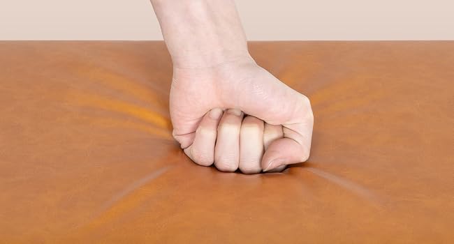 Primer plano de una mano humana haciendo un puño sobre una superficie de madera marrón, que demuestra la posición de agarre o golpe. Tono de piel visible sobre un fondo de madera cálida.