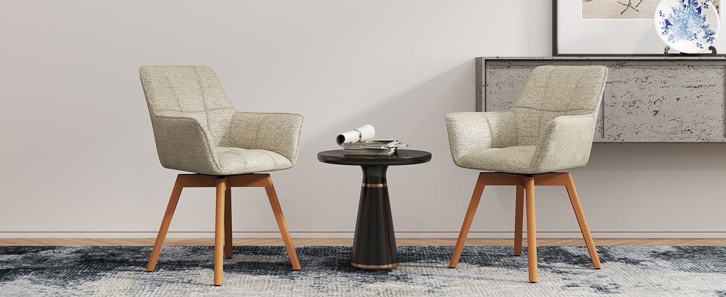 Deux chaises d'appoint rembourrées beiges avec pieds en bois positionnées autour d'une petite table d'appoint ronde noire contre un mur gris clair.