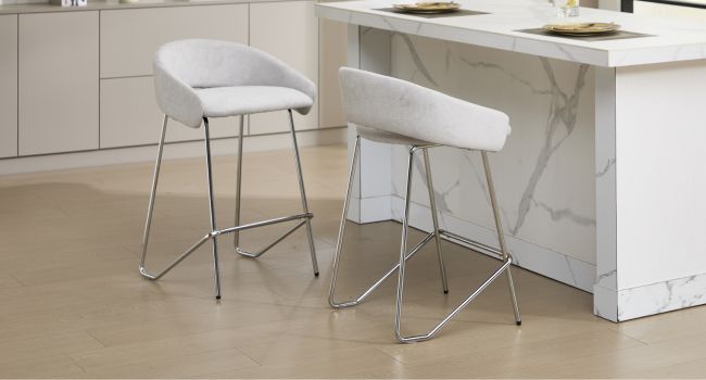Deux tabourets de bar blancs modernes dotés d'élégants cadres en fil métallique placés sur un comptoir de cuisine d'aspect marbre.