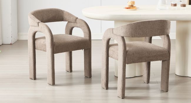 Deux fauteuils incurvés rembourrés beiges identiques au design arrondi moderne. Les chaises sont dotées d'un dossier incurvé et de coussins d'assise rembourrés.