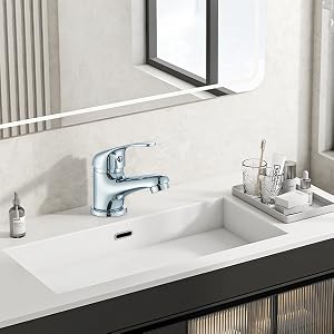 Modern bathroom vanity featuring white countertop with integrated sink basin and chrome faucet. Mirror and bathroom accessories visible.