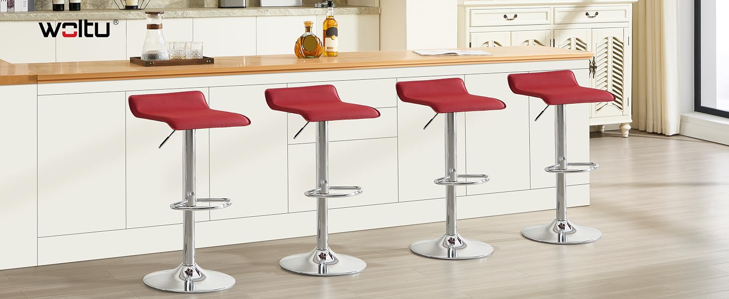 Quattro sgabelli da bar regolabili rossi con basi cromate disposti in fila lungo il bancone della cucina, caratterizzati da un moderno design girevole