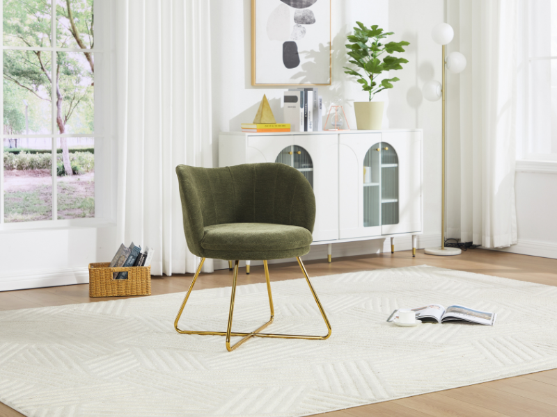 Silla decorativa moderna de color verde oliva con respaldo curvo y base de estructura de metal dorado, colocada sobre una alfombra con estampado de color beige en una habitación de color blanco brillante con ventana y unidad de almacenamiento decorativa.