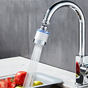 Chrome kitchen faucet with attached water filter aerator shown in action over a sink with produce visible.