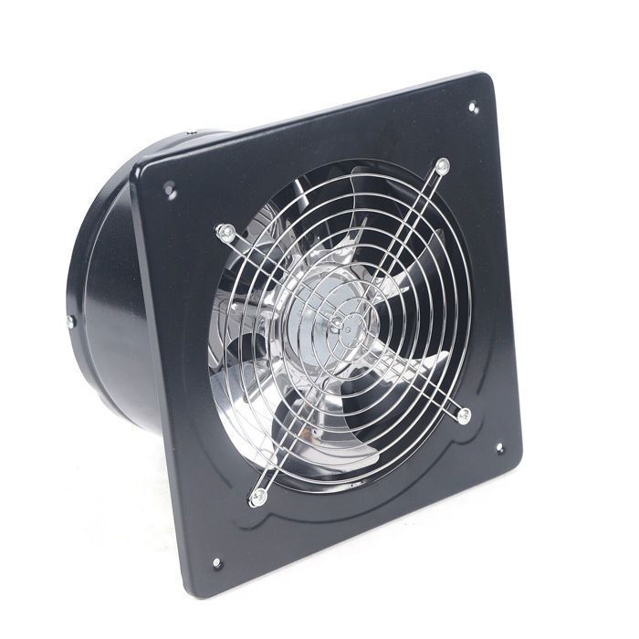 Ventilateur déchappement noir avec grille métallique circulaire et cadre carré, posé sur un sol clair devant une fenêtre. Des feuilles vertes flottent autour, suggérant un flux dair. Le produit est entièrement visible, avec un design compact et des vis de fixation aux coins du cadre.