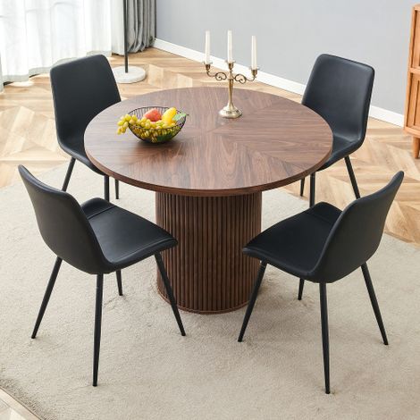 Ensemble minimaliste composé d'une table ronde et de quatre chaises. Table de salle à manger ronde en MDF de 100 cm de diamètre, aspect noyer. Chaises assorties revêtues de similicuir noir (PU). (1/5)