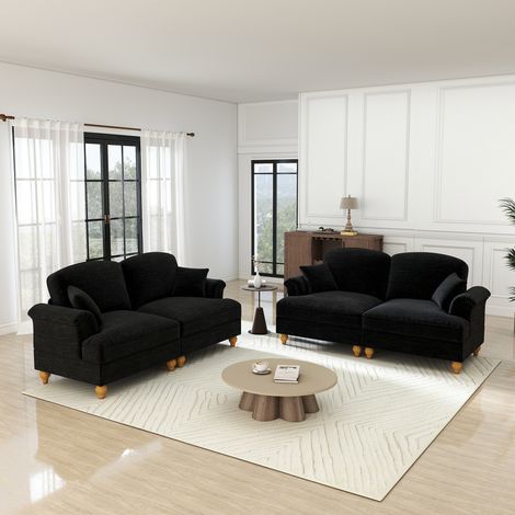 Elegante sofá de dos plazas en forma de L de mediados de siglo, tapizado en chenilla con reposabrazos en forma de embudo, faldón con volantes extraíble, patas torneadas y otomana móvil, color negro.